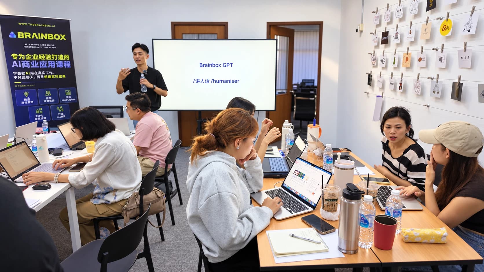 The mentor presenting in front of the screen with students around the tables