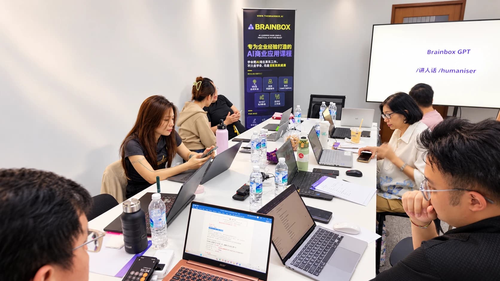 Students on both sides of a long table working on laptops